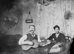 Paar am Wohnzimmertisch, wohl um 1900-10